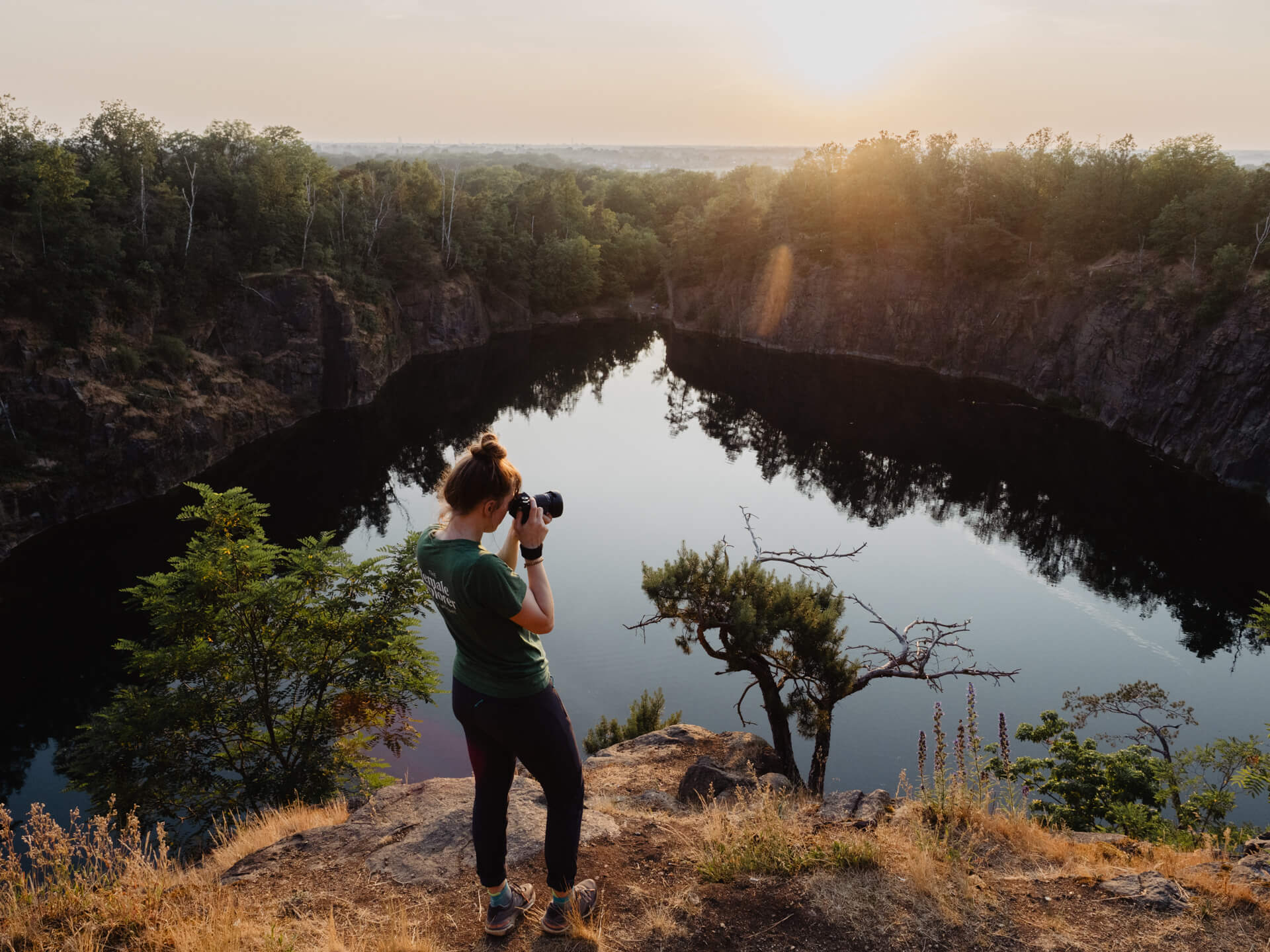 Outdoor-fotografie: Eine Frau steht vor einem See und hält eine Kamera vor dem Geschicht