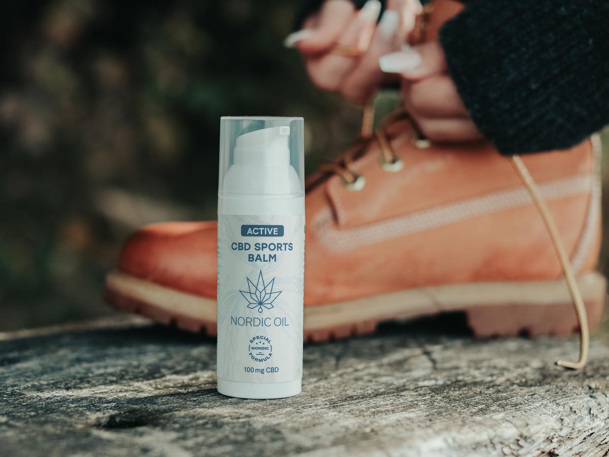 Wanderschuh im Hintergrund und Active CBD Sports Balm im Vordergrund